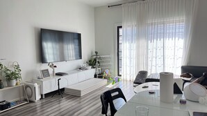 Een moderne woonkamer met een flatscreen televisie, een eettafel en een bank.
