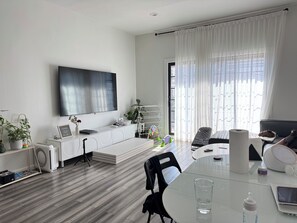 Ein modernes Wohnzimmer mit Flachbildfernseher, einem Esstisch und einer Couch.