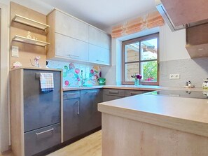 A modern kitchen with a large island, built-in appliances, and a window with a view. - Roiderhof by Interhome (Mondsee)