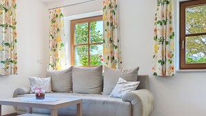 Ein Wohnzimmer mit einer Couch, einem Couchtisch und blumigen Vorhängen.
