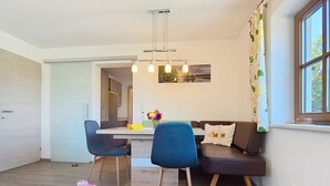 A modern living space with a dining area, a sofa, and a table with a decorative item.