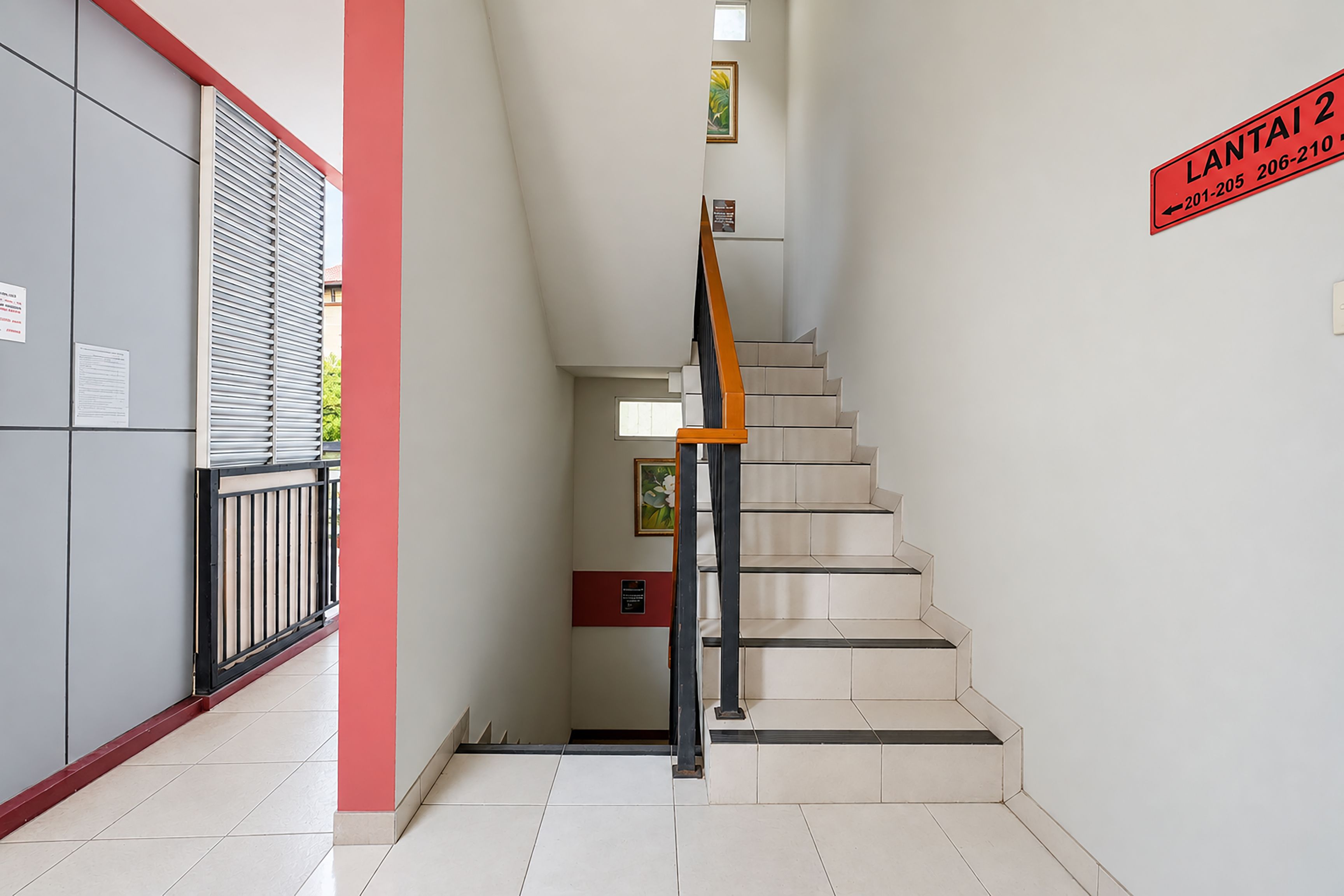 A staircase with a red handrail, a sign indicating 'LANTA 2' with a phone number, and a window with blinds.
