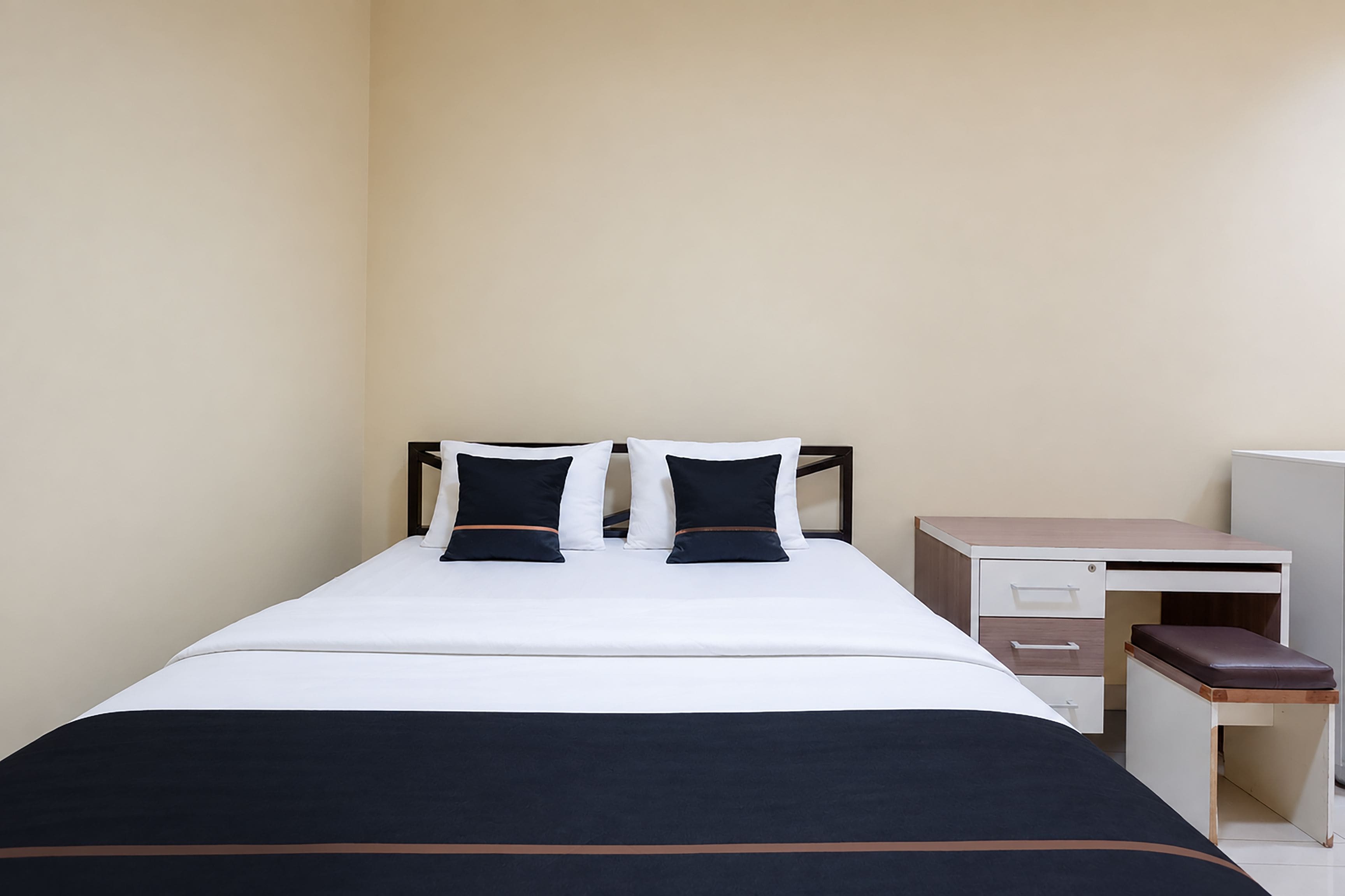 A single bed with a white and navy bedding, a wooden headboard, and two pillows.