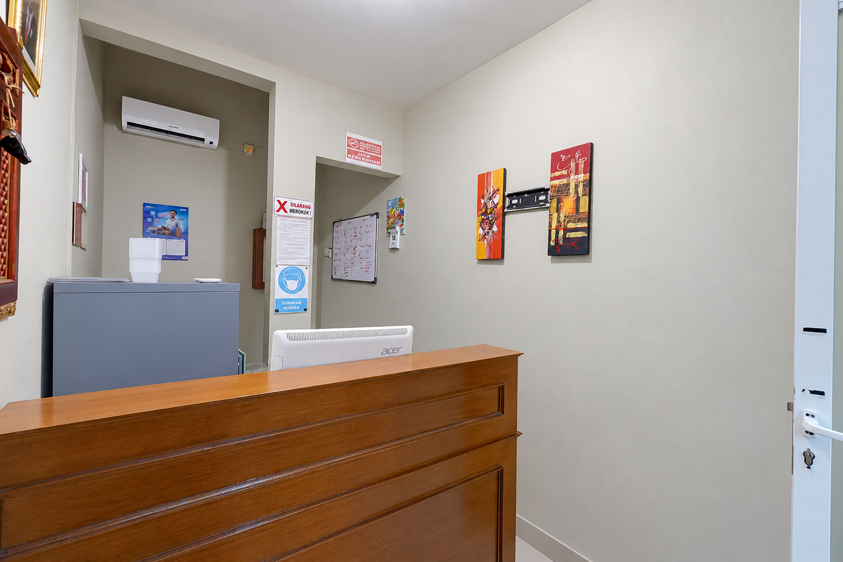 Un área de recepción con un escritorio de madera, una pizarra y un aire acondicionado de pared.