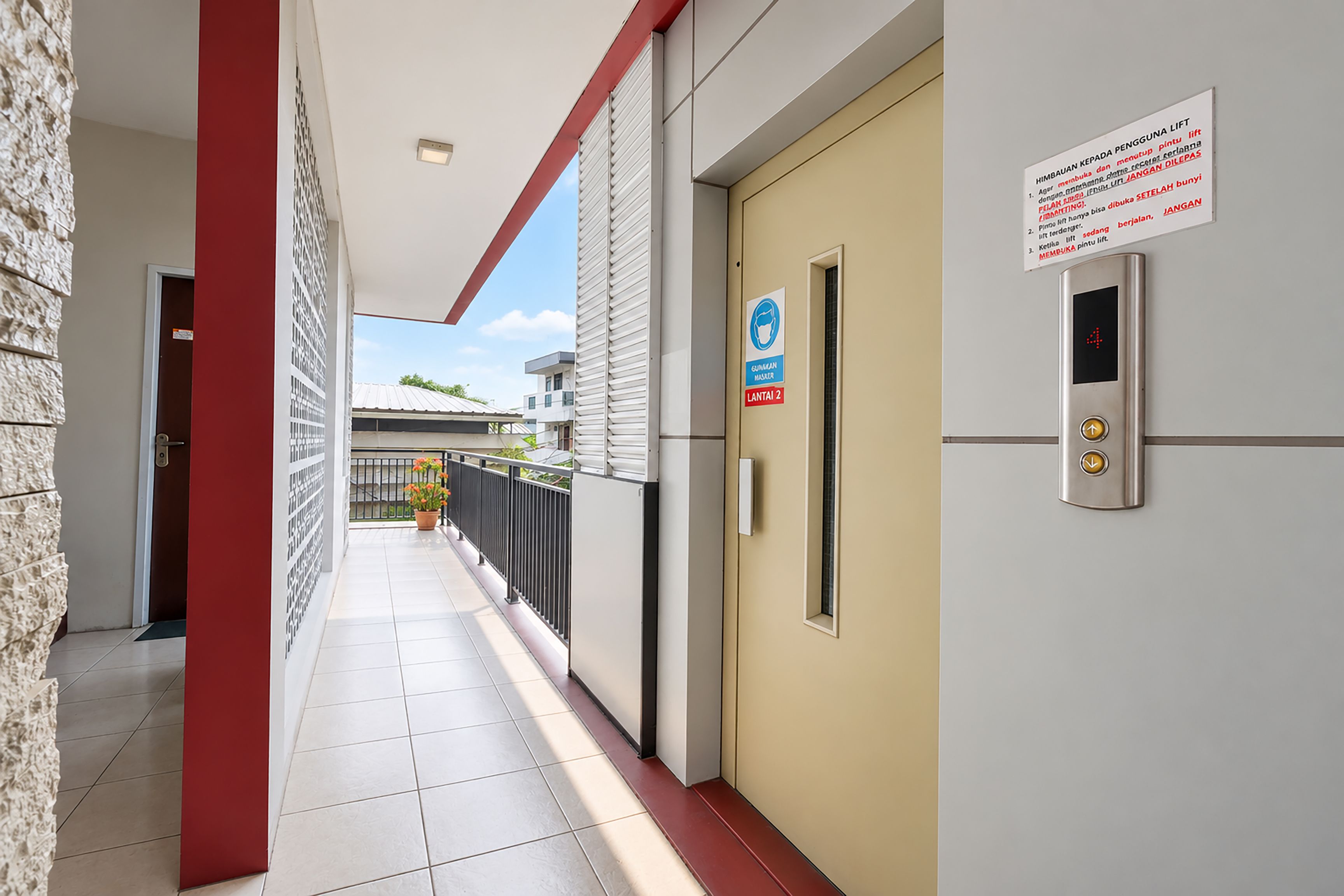 Un pasillo con un ascensor, un cartel que indica el uso obligatorio de mascarilla y una puerta con un número.