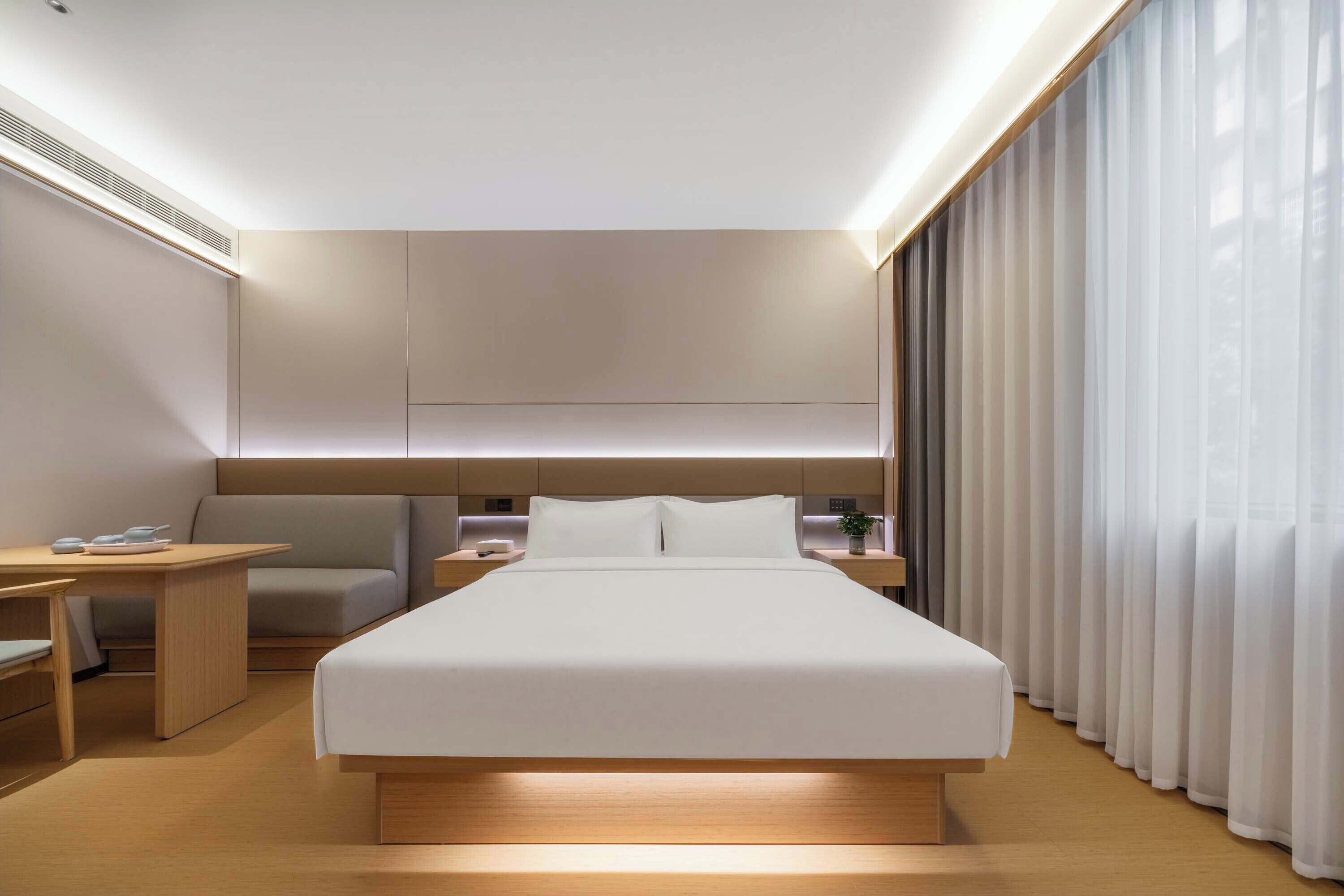Una habitación de hotel moderna con una cama grande, mesitas de noche, un escritorio y una silla.