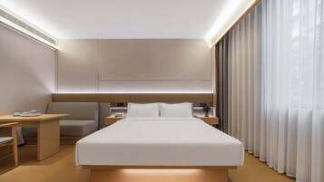 Una habitación de hotel moderna con una cama grande, mesitas de noche, un escritorio y una silla.