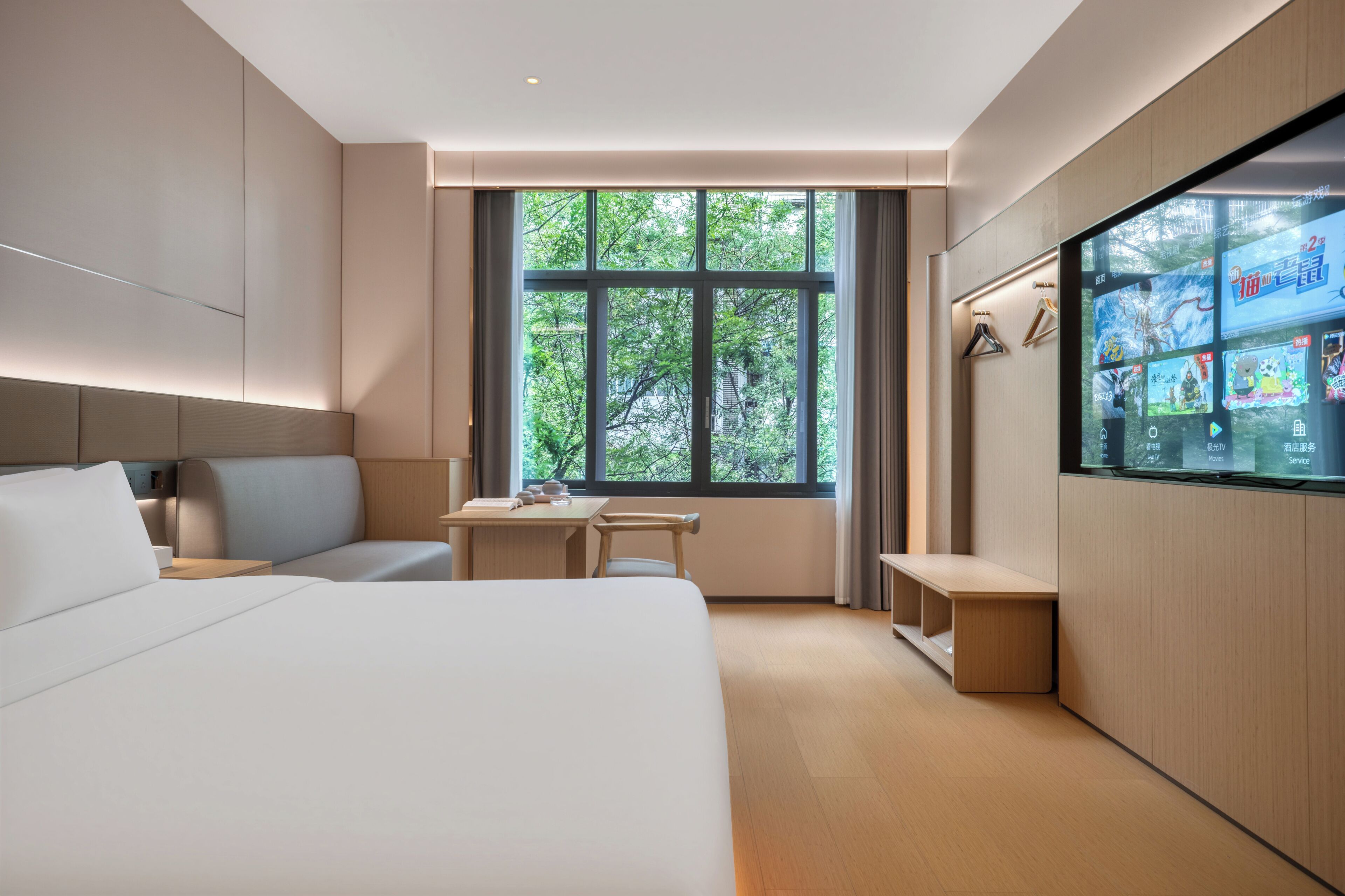 A modern hotel room with a large bed, a desk, and a TV mounted on the wall.