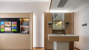 Un baño moderno con un espejo grande, un lavamanos y una pantalla de televisión integrada que muestra varios canales.