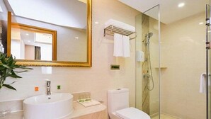 A modern bathroom with a large mirror, two sinks, a toilet, and a glass-enclosed shower. - Vienna Hotel (Nanjing)