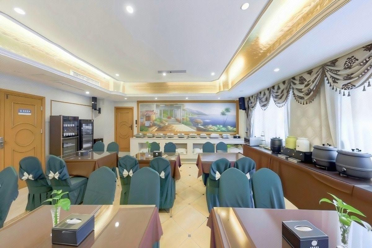 Un salón de conferencias con mesas y sillas, un cuadro grande en la pared y una zona de buffet con equipo de cocina.