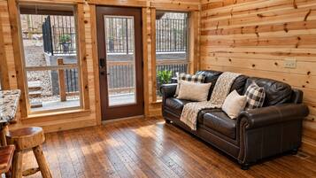 Un interior de madera con un sofá de cuero, una mesa de madera y una puerta que da al exterior.