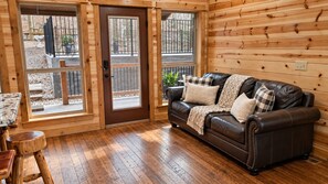 Un intérieur en bois avec un canapé en cuir, une table en bois et une porte donnant sur l’extérieur.