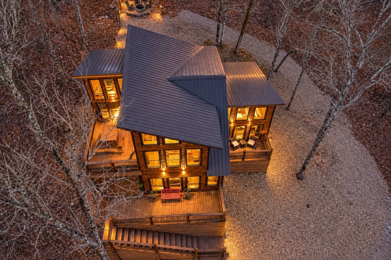 A multi-level wooden cabin with multiple decks and large windows, surrounded by trees.