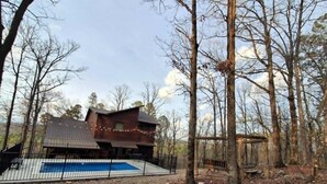 Una cabaña con piscina, rodeada de árboles.