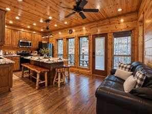 A cabin interior with a kitchen, dining area, and a living room with a leather sofa. - Three Bears – Mountainside Cabin with Private Heated Pool & Hot Tub (Broken Bow)