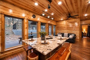 A spacious wooden interior with a large dining table, seating, and a view of the outdoors. - Three Bears – Mountainside Cabin with Private Heated Pool & Hot Tub (Broken Bow)