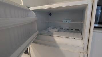 An open refrigerator with shelves and a freezer compartment.