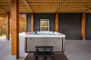 Ein Whirlpool unter einer Holzpergola mit Blick auf Herbstbäume.