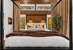 A bedroom with a four-poster bed, a large window with curtains, and a view of autumn foliage. - Bluebird Reserve: Dome • Sauna • Hot-Tub • Cold Plunge • Fire-Pit • Putt • Views (Mineral Bluff)