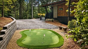 A well-maintained golf course with a putting green, surrounded by a stone wall and a wooden building. - Bluebird Reserve: Dome • Sauna • Hot-Tub • Cold Plunge • Fire-Pit • Putt • Views (Mineral Bluff)