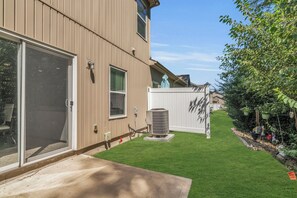 A residential building with a garage door, a small air conditioning unit, and a well-maintained lawn.