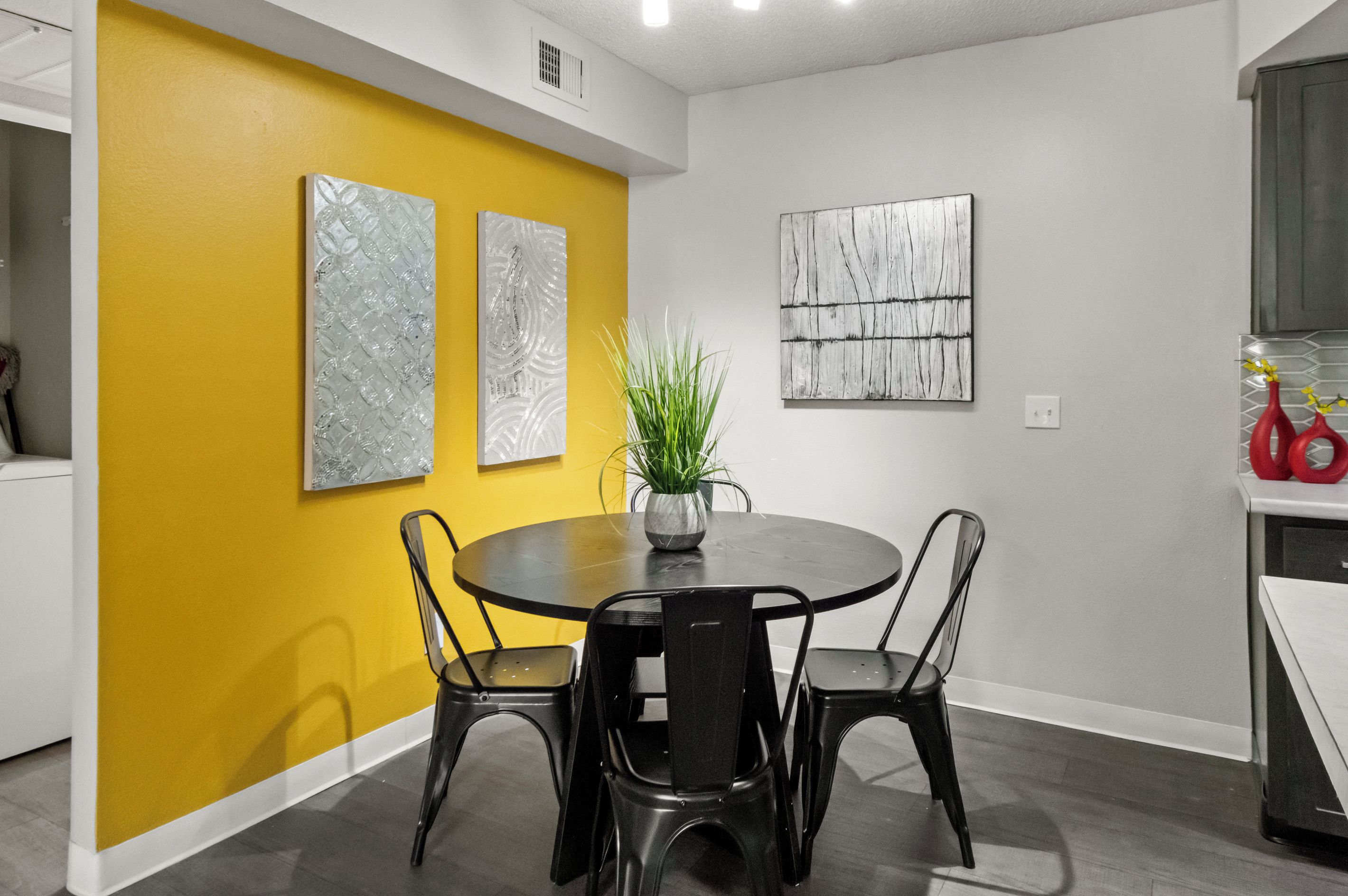 A dining area with a round table, four chairs, and two wall-mounted artworks.