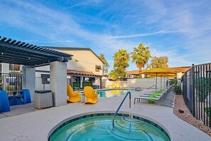 Un espace piscine avec un jacuzzi, des chaises jaunes et un coin salon abrité.