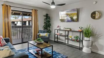 Un salon comprenant un canapé, une table basse, un téléviseur et une porte-fenêtre coulissante donnant sur un espace extérieur.