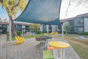 An outdoor patio area with a foosball table, seating, and a shaded area.