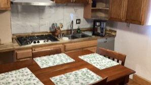 Une cuisine avec des meubles de rangement en bois, une cuisinière, un évier et une machine à café.