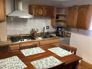 A kitchen with wooden cabinets, a stove, a sink, and a coffee maker. - Cozy 1-bedroom apartment in beautiful Albuquerque with AC private gated parking (Albuquerque)