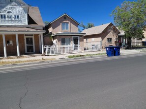 A residential street with houses, a white fence, and a blue dumpster. - Cozy 1-bedroom apartment in beautiful Albuquerque with AC private gated parking (Albuquerque)