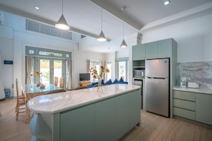 A modern kitchen with a large island, built-in appliances, and pendant lighting.