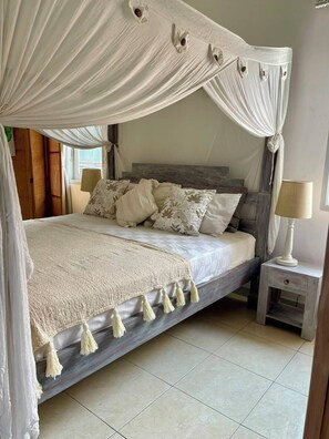 A bed with a canopy, a bedside table, and a lamp.