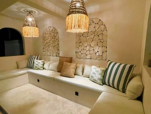 A modern living room with a sectional sofa, decorative wall art, and hanging lamps.