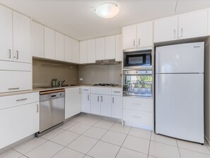 Eine moderne Küche mit weißen Schränken, einem eingebauten Ofen, einer Mikrowelle und einem Kühlschrank.