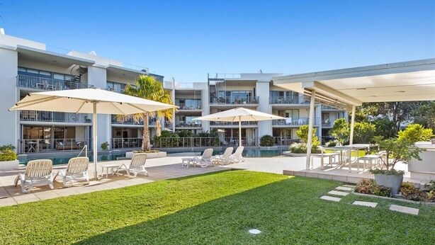 Un hotel moderno con zonas de estar al aire libre, piscina y césped cuidado.