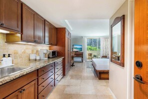 Une chambre d’hôtel équipée d’une kitchenette, d’un lit, d’une télévision et offrant une vue sur l’extérieur.