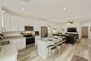 A modern kitchen with white cabinetry, stainless steel appliances, and a central island with bar stools. - Peaceful 3BR Getaway | Pines, Wildlife, Hiking & Golf (Payson)