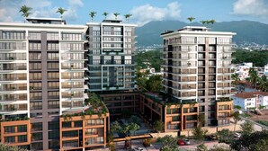 Un moderno edificio residencial de varios pisos con balcones, un patio central y vistas a un paisaje montañoso.