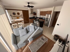 Un salon moderne avec un canapé gris, une table basse et un ventilateur de plafond.
