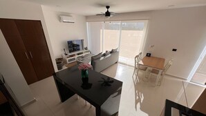 Una cocina moderna con comedor, televisor y un amplio ventanal.
