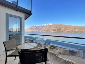 A balcony with a table and chairs, overlooking a lake and mountains. - Lakeview Townhouse | Relax Above Queenstown (Queenstown)