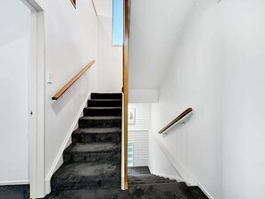 Eine Treppe mit hölzernem Geländer und Teppichstufen, die zu einer Tür führen.