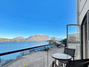 A balcony with a table and chairs overlooking a lake and mountains. - Stunning Lake Views | Sunny Corner Townhouse (Queenstown)