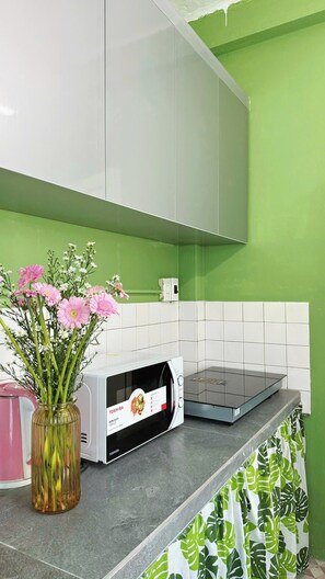 Eine Küche mit Mikrowelle, Blumen in einer Vase und einer grünen Wand.