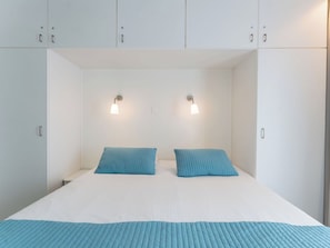 Une chambre à coucher avec un lit, deux oreillers et deux lampes fixées au mur.