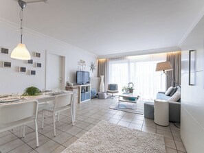 Ein modernes Wohnzimmer mit Essbereich, einem Flachbildfernseher und einer Couch.