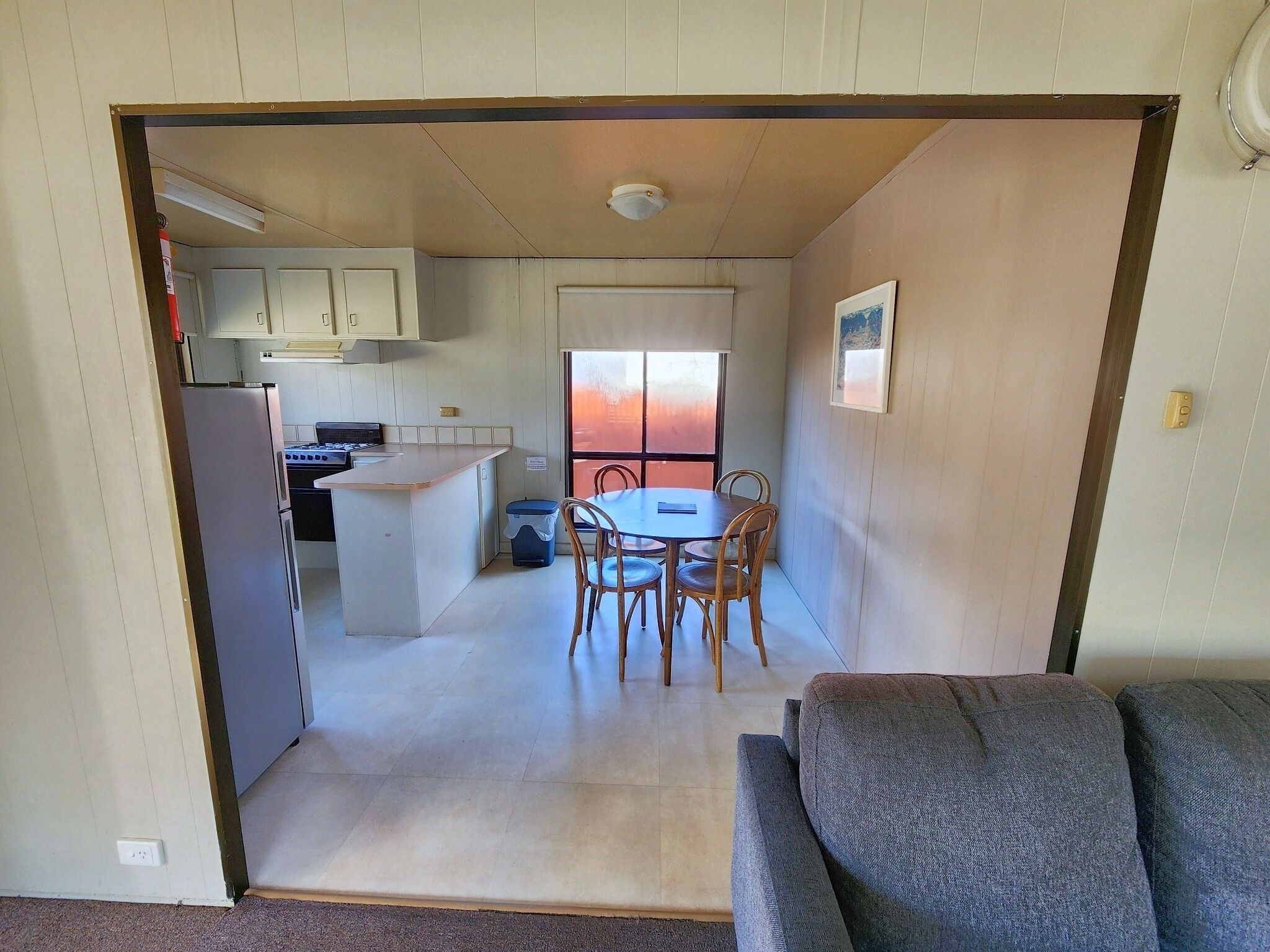 A compact kitchen with a dining area, a sofa, and a window with a view.